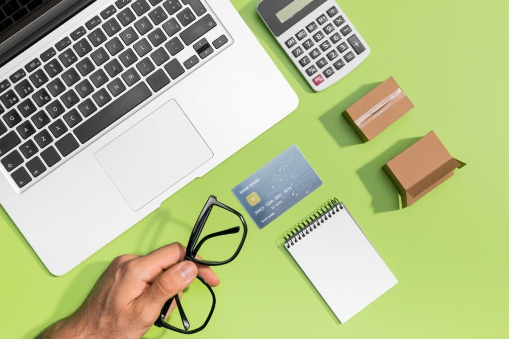 a hand holding glasses next to a laptop and a calculator